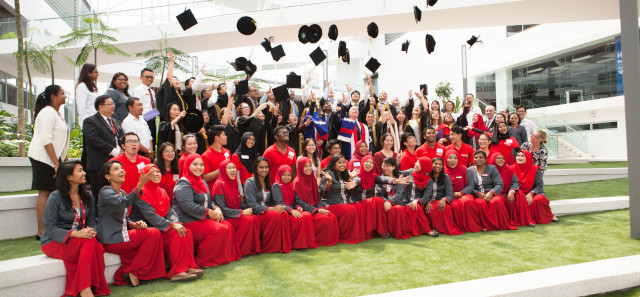 一群在毕业典礼上穿着红色长袍的学生。他们中的一些人把帽子抛向空中。