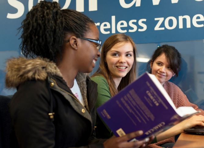 三个女学生一起在大学图书馆学习。
