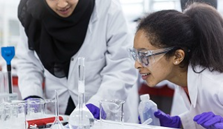 学生们用实验室玻璃器皿、白大褂和护目镜进行科学实验