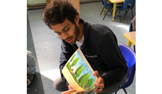 一名学生志愿者给幼儿园的孩子们读故事